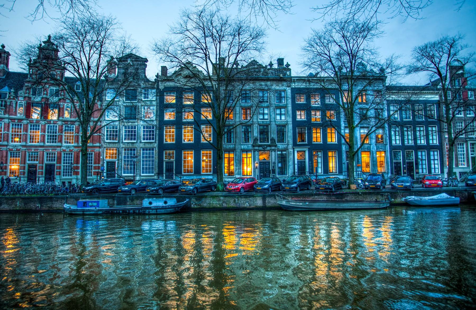 Canal houses reflected in an Amsterdam canal at dusk